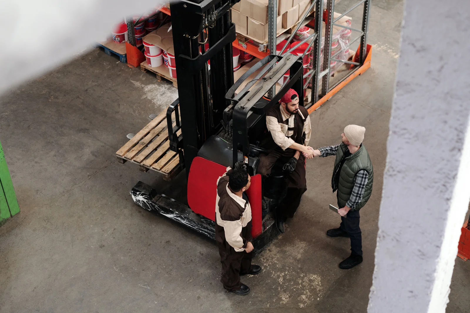 Warehouse colleagues discussing work beside handling equipment.
