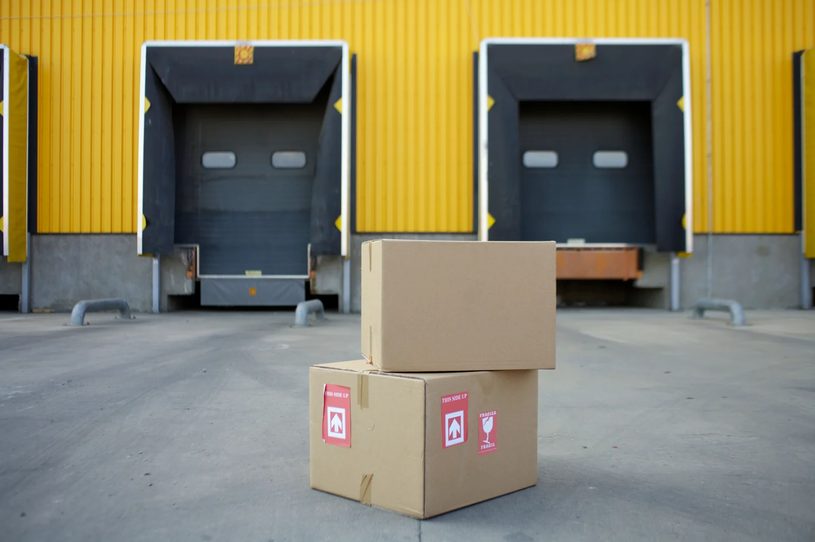 Cardboard parcels stacked outside warehouse loading doors.