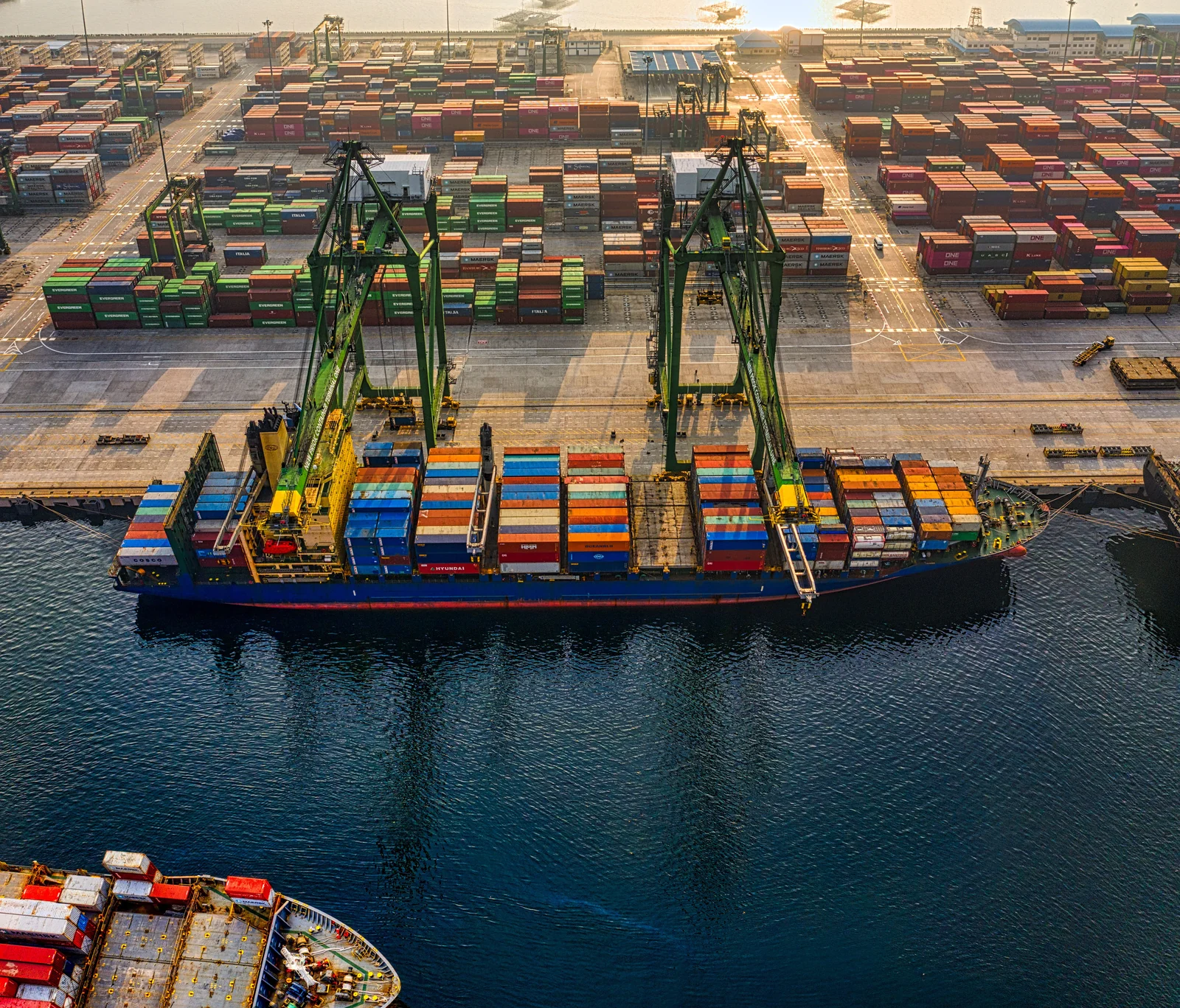Overhead view of a container vessel alongside a busy port terminal.