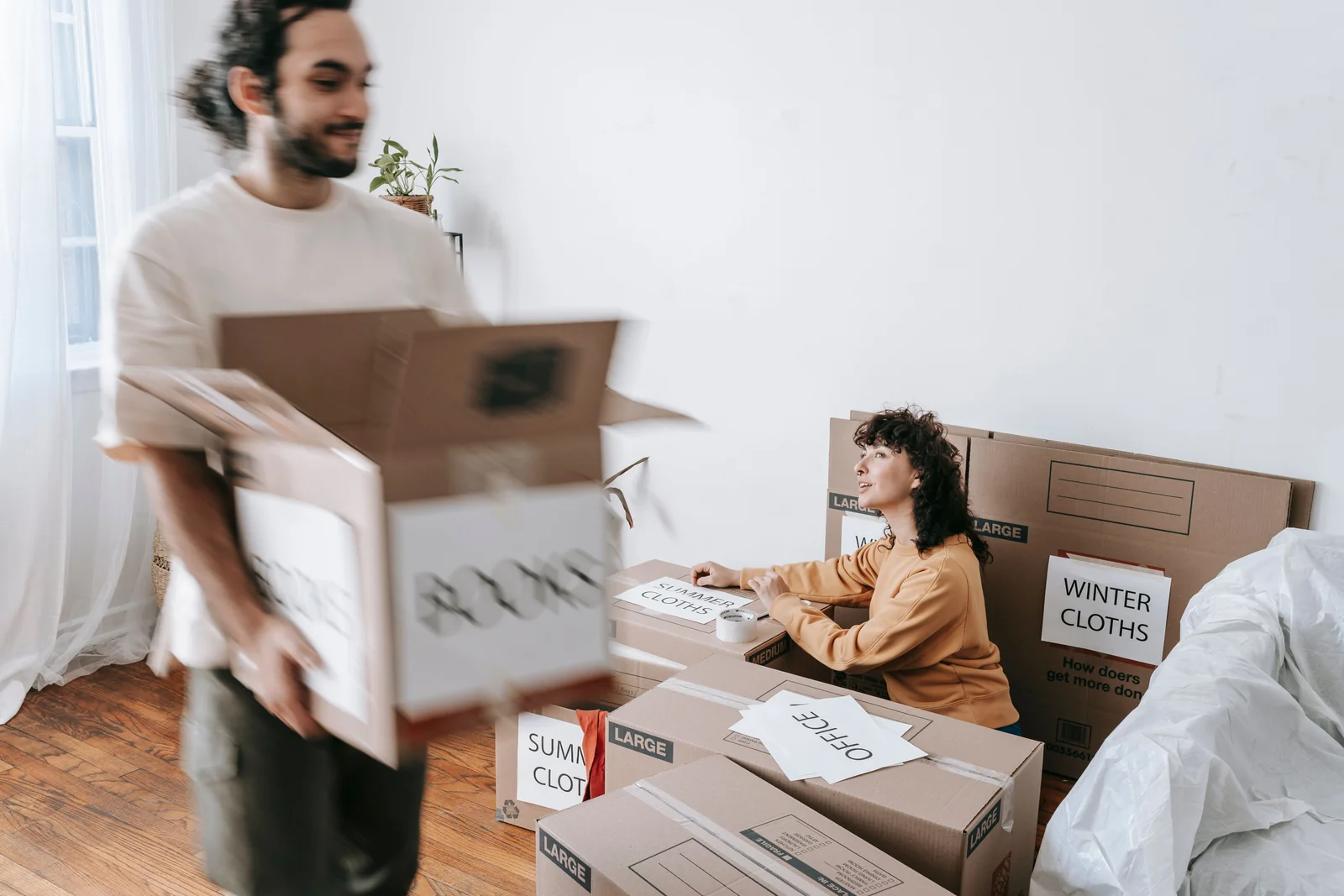Two people packing household belongings into moving boxes.
